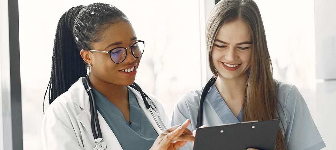 two healthcare professionals smiling as they review patient information.