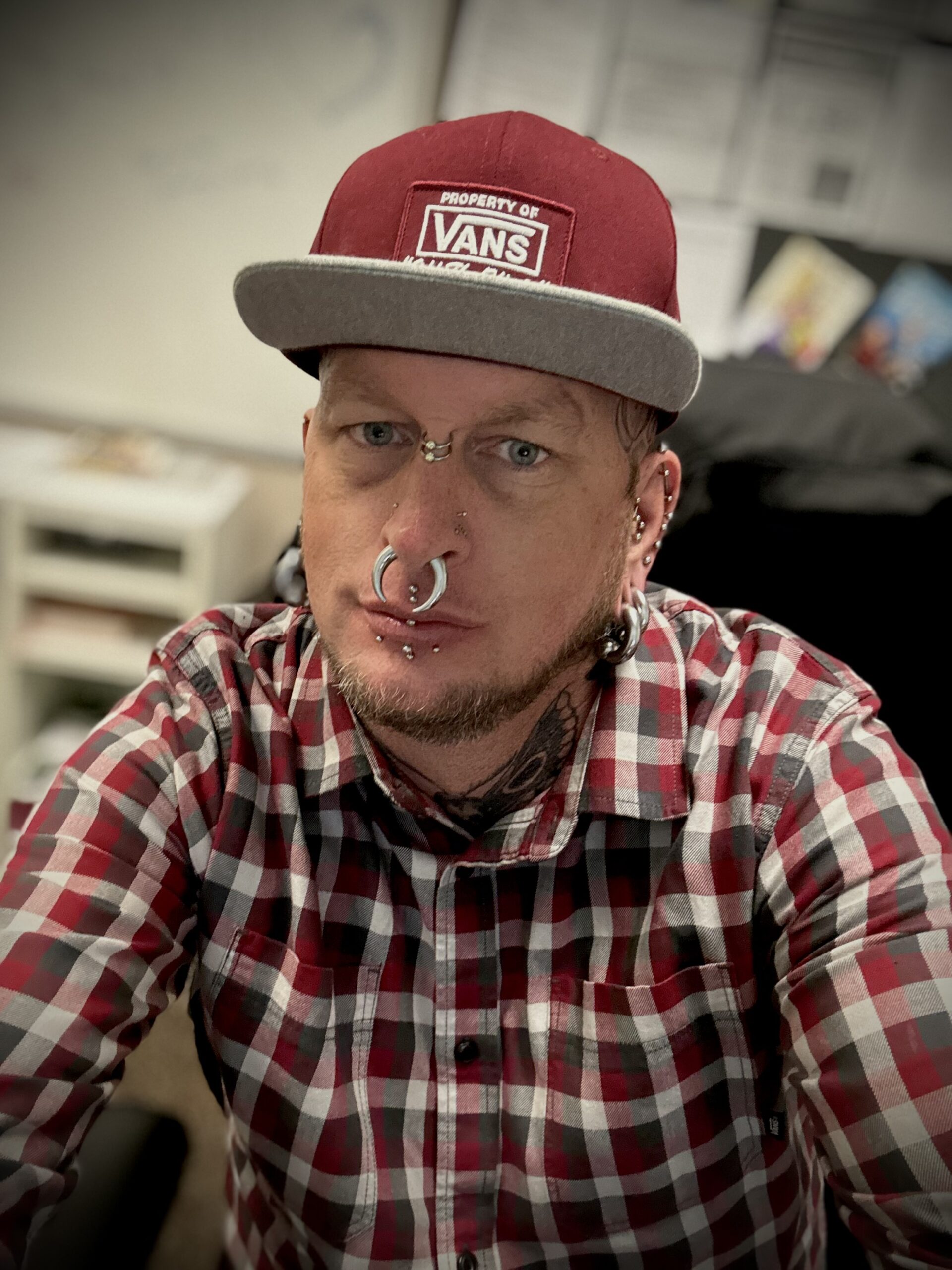 photo of Reinhardt, a white man wearing a red hat and shirt with facial piercings.